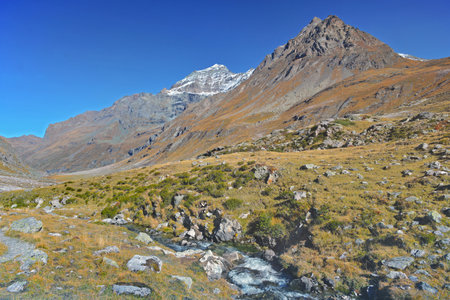 peak mountain in a valley crossing by a little streaming in European Alpsの写真素材