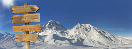wooden sign and panoramic view on snowy peak mountain under sunny blue skyの写真素材