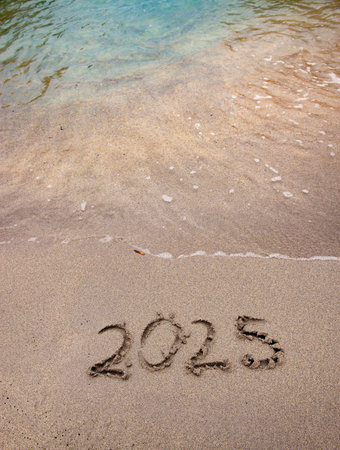 2025 text handwriting on the sand in a beach with a wave at ocean beach shoreの写真素材