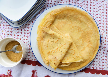 top view on traditional french pancake homemade- folded crepe in a plate on a red and white tableclothの写真素材
