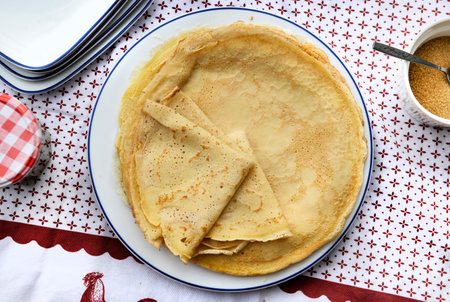 top view on traditional french pancake homemade- folded crepe in a plate on a red and white tableclothの写真素材
