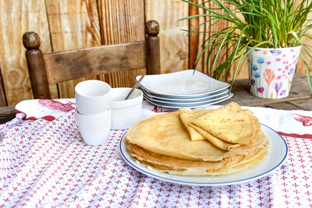 traditional french homemade pancakes in a plate served on a table with red and white tablecloth on rustic wooden decorの写真素材