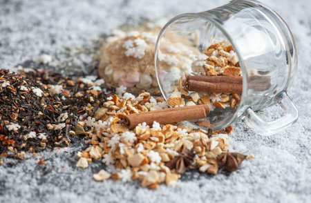 winter hot drink ingredient spiced with spices, star-shaped and sugar and glass cup turn over on snowy backgroundの写真素材