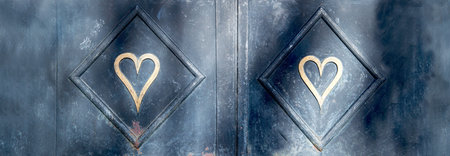two golden heart shaped on dark metal background in a frameの写真素材