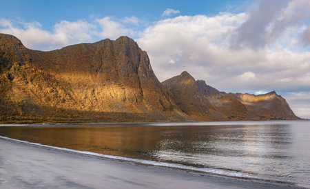 view from the beach on large mountains in a fjork at Skaland in the Senja island in Norway illuminated by the sunの写真素材