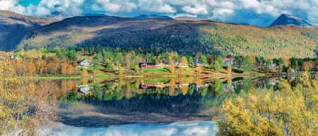 beautiful scenic autumnal landscape in Norway with mountain and few houses at the edge of waterの写真素材