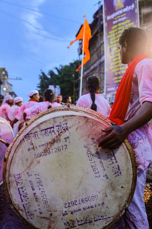 A selective focus image of a group of men playing dhol a musical instrument and dancing in a religious procession of Ganesh visarjan in pune Maharashtra India on 12 September 2019.のeditorial素材