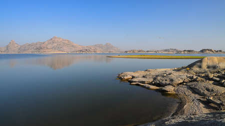 A selective focus image of a  landscape of Jawai dam with clear blue sky and Aravalli mountain ranges with its reflection in water at Jawai in Rajasthan  Indiaの写真素材
