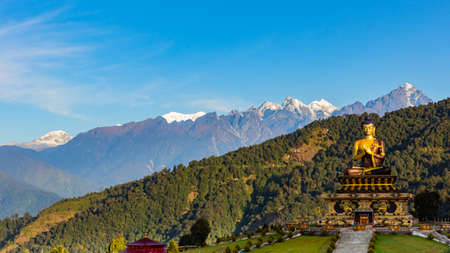 A selective focus image of Buddha statue at Buddha park with snow clad himalayan mountain range in the background as seen from Rabongla in Sikkim Indiaの写真素材