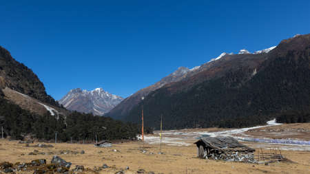 A selective focus image of a hut made of stones with Tibetan prayer flags in front at the valley of flowers in sikkim Indiaの写真素材