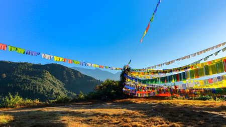 Tibetan prayer flags blowing with the wind with high mountain ranges in the background lit with sun at the valley of flowers in Sikkim Indiaの写真素材