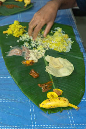 Traditional Kerala food being eaten on a banana leaf during the Onam festival in Kerala Indiaの写真素材