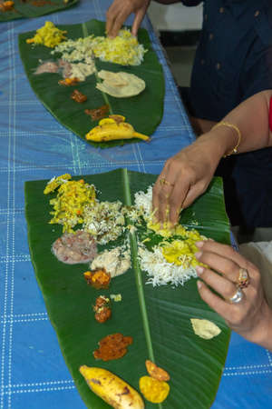 Traditional Kerala food being eaten on a banana leaf during the Onam festival in Kerala Indiaの写真素材