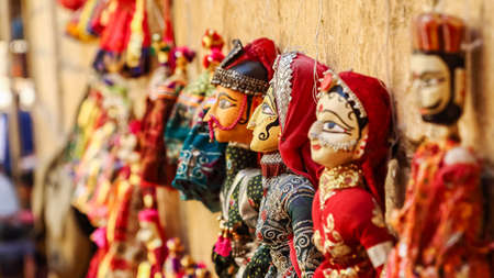 Colorful human face shaped Puppets wearing colorful clothes hanging against the wall in Rajasthan India on 21 February 2018の写真素材
