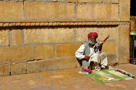 A man wearing turban is siting on ground and playing vilolin at Jaiselmer Rajasthan India on 21 February 2018のeditorial素材