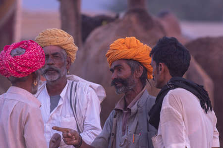 A group of men wearing turbans standing and speaking to each other at Pushkar, Rajasthan, India on 18 November 2018のeditorial素材