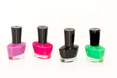 Shallow depth of field image of Four bottles of colored nail polish kept in a pattern with white backgroundの写真素材