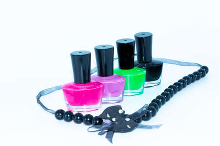 Selective focus image of Nail polish bottles of different colors and a beautiful necklace around it with white backgroundの写真素材