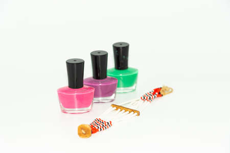 Selective focus Narrow depth of field Macro image of three bottles of colored nail polish and a brace-late  with white backgroundの写真素材