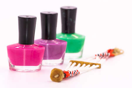 Selective focus Narrow depth of field Macro image of three bottles of colored nail polish and a brace-late  with white backgroundの写真素材