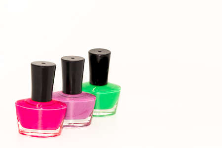 Shallow depth of field image of Three bottles of colored nail polish kept on display with white backgroundの写真素材
