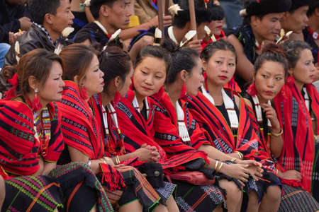 Selective focus image of young Naga tribeswomen siting together wearing colorful attire and shawls...