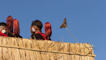 Naga men siting with  their traditional weapons and a butterfly stuck in a twig at a village at Kohima Nagaland India on 4 December 2016のeditorial素材