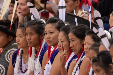 Selective focus image of young Naga tribeswomen siting together wearing colorful attire and shawls in Kisama Heritage village in Nagaland India on 3 December 2016のeditorial素材