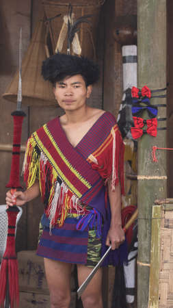A Young Naga tribseman dressed in traditional attire with traditional weapons at Kohima Nagaland...