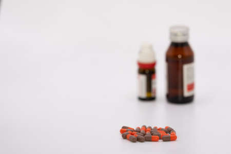 Selective focus Macro image of red and black capsules with medicine bottles kept in the backgroundの写真素材