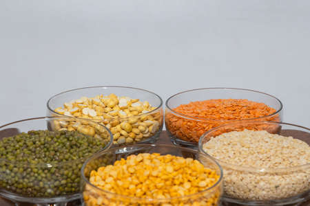 Side view of assorted varieties   lentils kept in different bowls on a wooden table