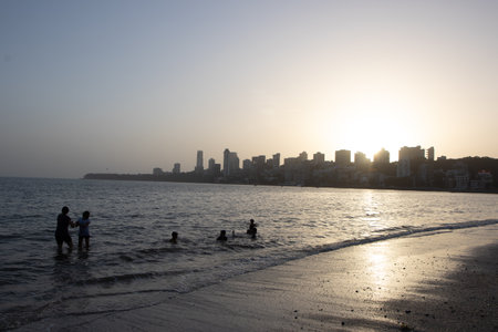 Silhouettes of people and skyscrapers during sunset at Marine drive Beach in Mumbai Maharashtra India on 2 April 2021のeditorial素材