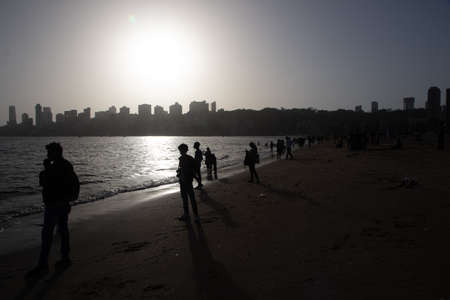 Silhouettes of people and skyscrapers during sunset at Marine drive Beach in Mumbai Maharashtra...