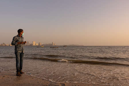 A man standing at Marine Drive Beach wearing a mask and following the COVID protocols in Mumbai India on 2 April 2021のeditorial素材