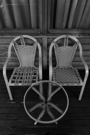 A pair of chairs and a round table with glass kept alongside each otherの写真素材