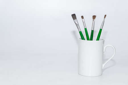 Oil color paint or water color paint brushes kept inside a white ceramic mug holderの写真素材