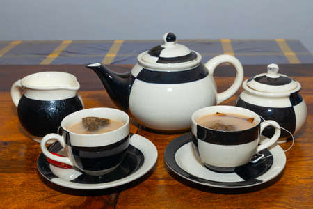 Milk Tea served in a ceramic tea set with design and tea bags insideの写真素材