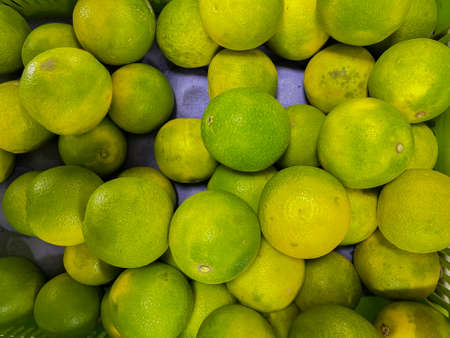Fresh Green and yellow heap of Sweet limes kept in a shelfの写真素材
