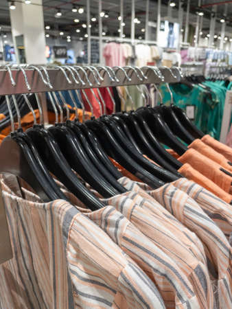 Selective focus image of colorful clothes hanging on the hangers in a rowの写真素材