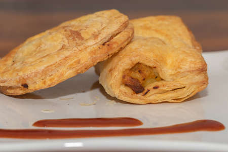 Close up Side Angle image of Baked puffs also called patties served on a white plate with tomato...