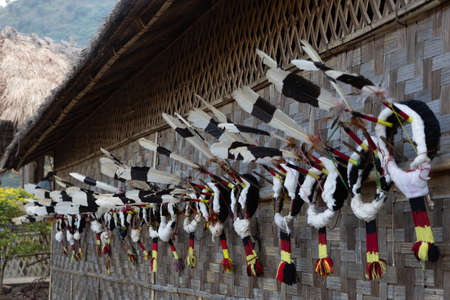 Traditional Naga head gear made of Hornbill feathers hanging on the wall of a traditional Naga hutの写真素材
