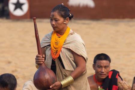 Naga men and women siting and performing a traditional tribal ritual in Kisama heritage village in Nagaland India during hornbill festival on 4 December 2016のeditorial素材