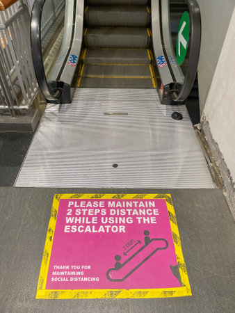 A sign on the floor near an escalator to caution people to maintain social distancing due to virus