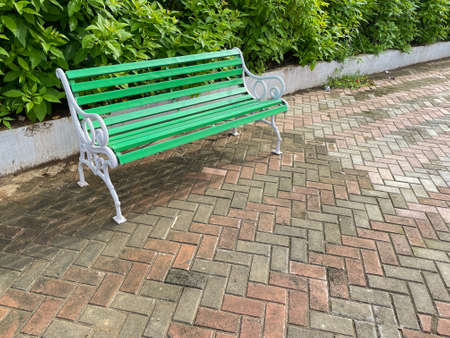 A beautiful bench painted green and white placed in a park with quite and green surroundingsの写真素材