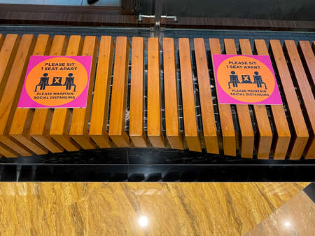 A wooden siting bench marked with social distancing norms while sitingの写真素材
