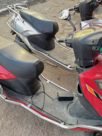 Two electric scooter charging with cable plugged in to itの写真素材