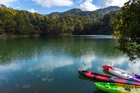 Colorful boats on the shore of a lake with the reflection of sky and hillsの写真素材