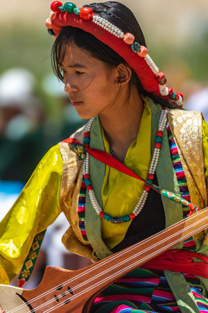 Portrait of a young Ladakhi girl in traditional attire playing a traditional musical Instrument at Leh, Ladakh India on 23 May 2024.のeditorial素材