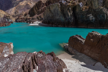 Jagged rock in the foreground with clear water and mountains in the background.の写真素材