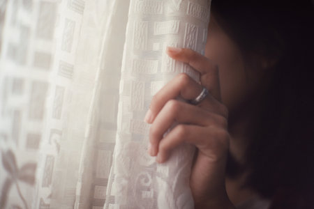 Closeup of a young woman looking through the window, selective focusの写真素材